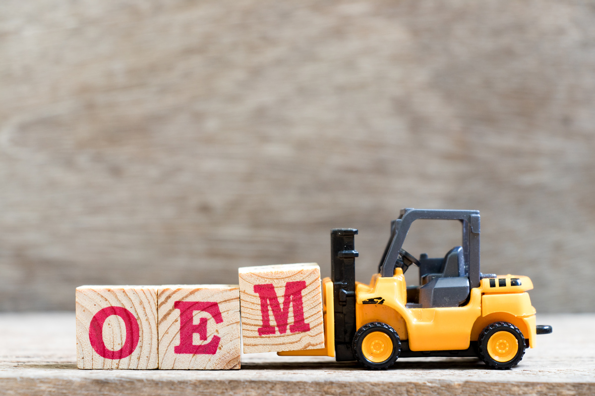 Toy forklift hold letter block M in word OEM (abbreviation of original equipment manufacturer) on wood background